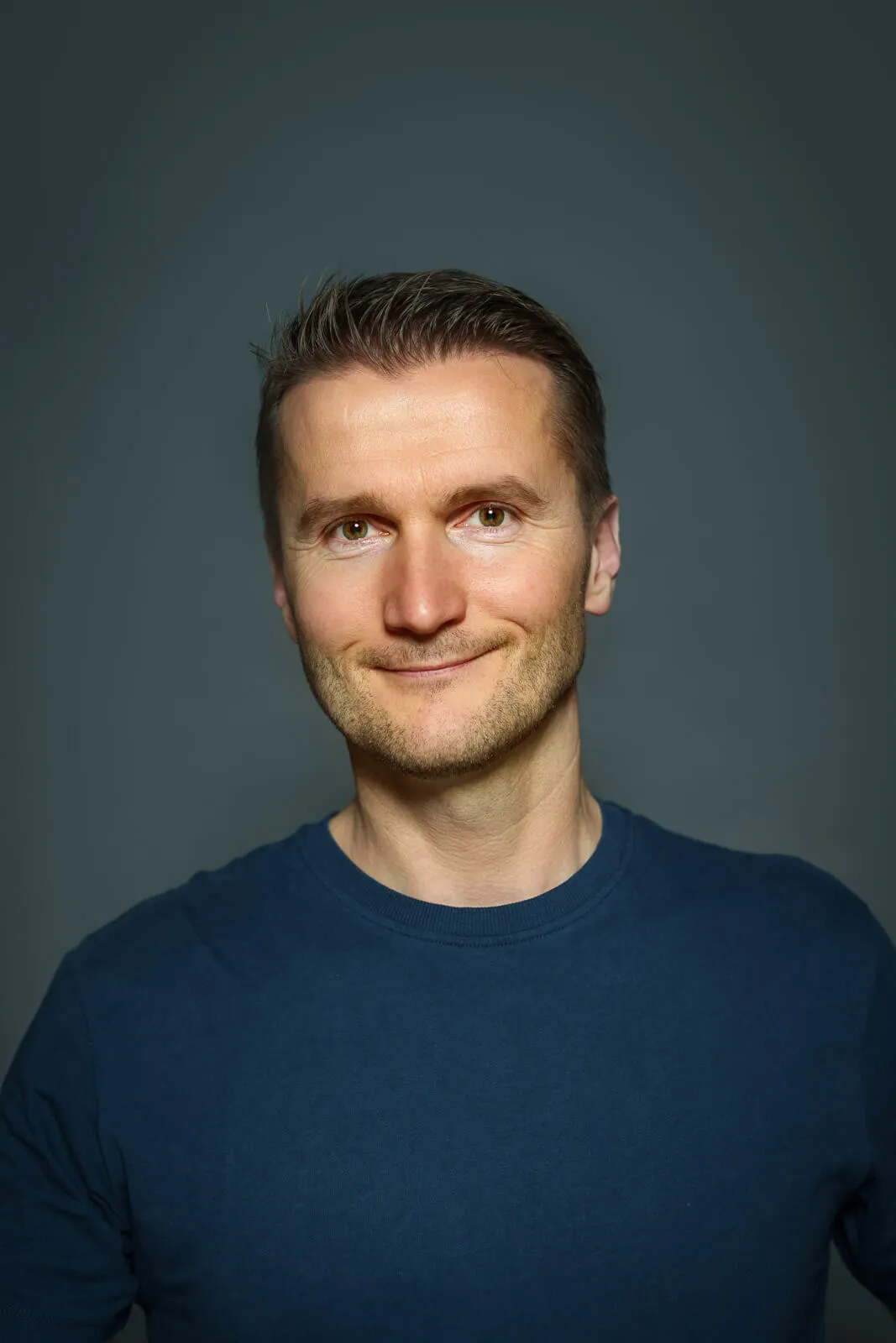 a man in a blue shirt smiling at the camera
